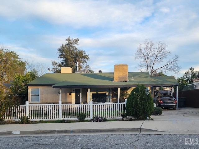 view of front of property featuring an attached carport, a porch, a chimney, and fence