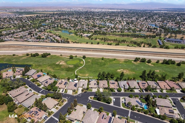 aerial view of property's location featuring nearby suburban area, a nearby body of water, and a golf course