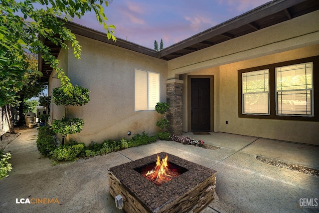exterior entry at dusk with stucco siding and a patio