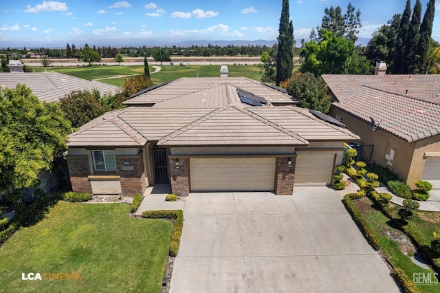 ranch-style home featuring a garage, brick siding, concrete driveway, a tiled roof, and a front lawn