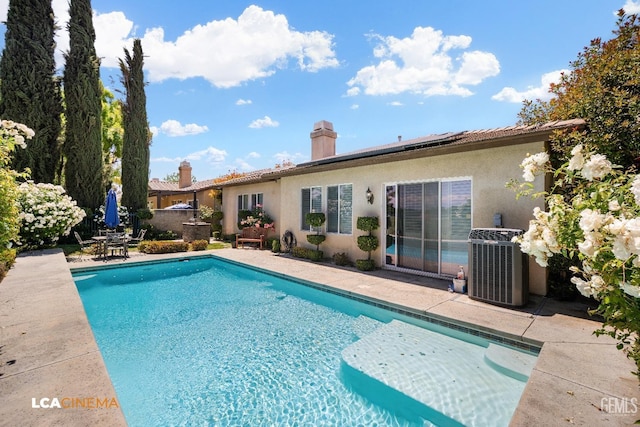 outdoor pool featuring cooling unit and a patio