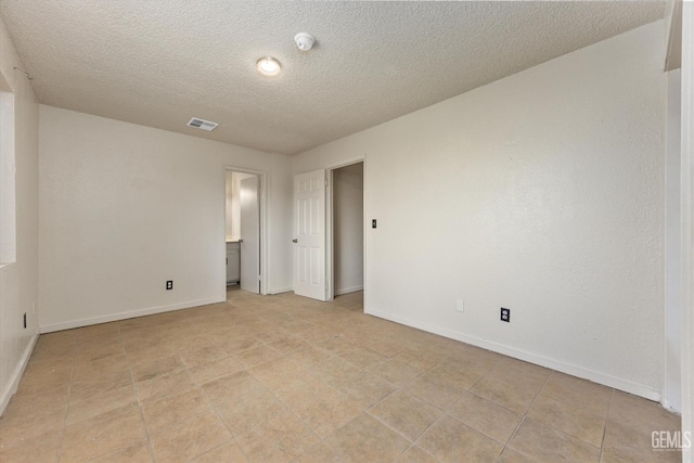spare room with a textured ceiling, baseboards, and visible vents