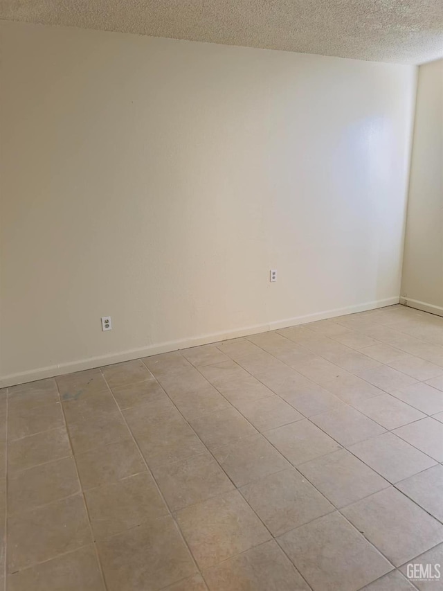 spare room with baseboards and a textured ceiling