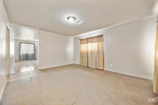 spare room with a healthy amount of sunlight, light tile patterned floors, baseboards, and visible vents