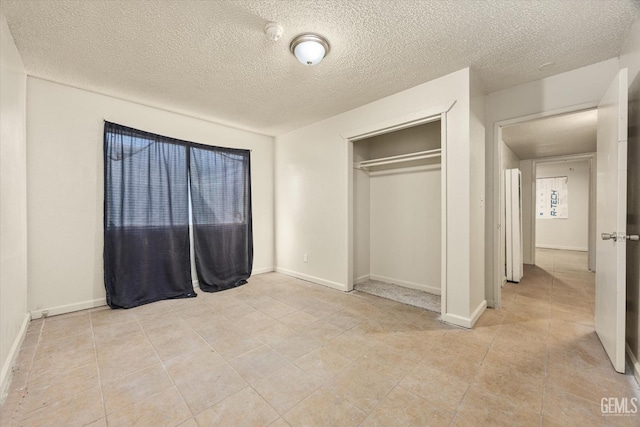 unfurnished bedroom with a closet, baseboards, a textured ceiling, and light tile patterned flooring