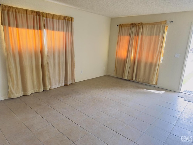 spare room with light tile patterned flooring and a textured ceiling