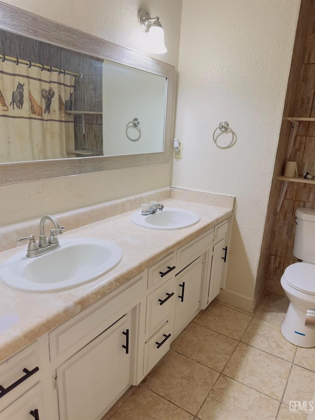 bathroom featuring double vanity, tile patterned flooring, a sink, and toilet