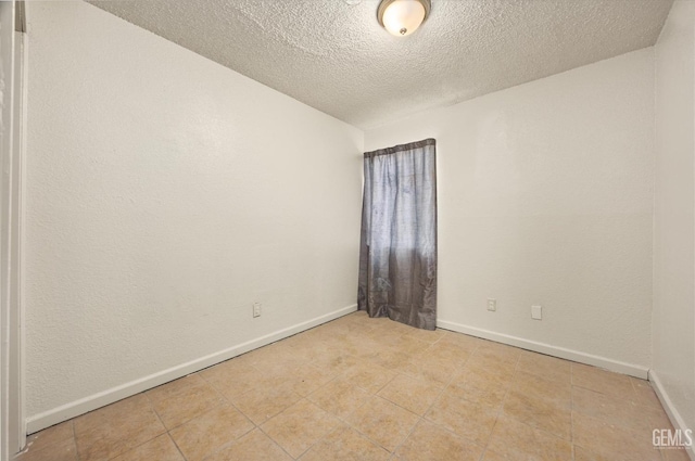 unfurnished room with a textured ceiling and baseboards