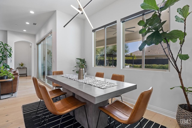 dining area with plenty of natural light, an inviting chandelier, and light hardwood / wood-style flooring