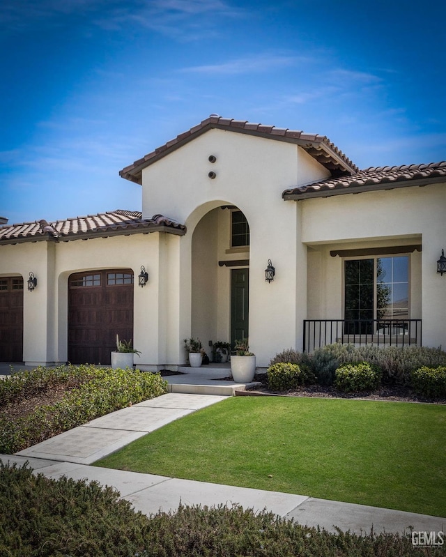 mediterranean / spanish house with a porch, a garage, and a front lawn