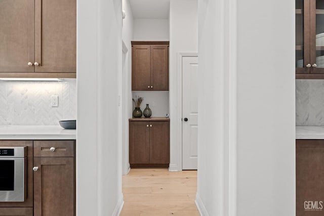 kitchen featuring oven, light wood-type flooring, and decorative backsplash