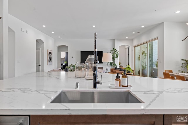 kitchen with light stone countertops, sink, and an island with sink