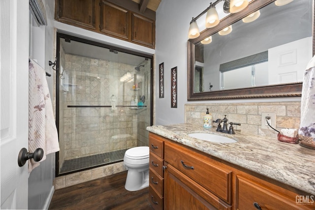 bathroom with hardwood / wood-style flooring, a shower with door, tasteful backsplash, vanity, and toilet