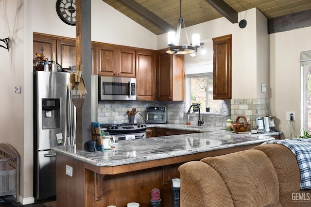 kitchen featuring sink, hanging light fixtures, stainless steel appliances, light stone countertops, and kitchen peninsula