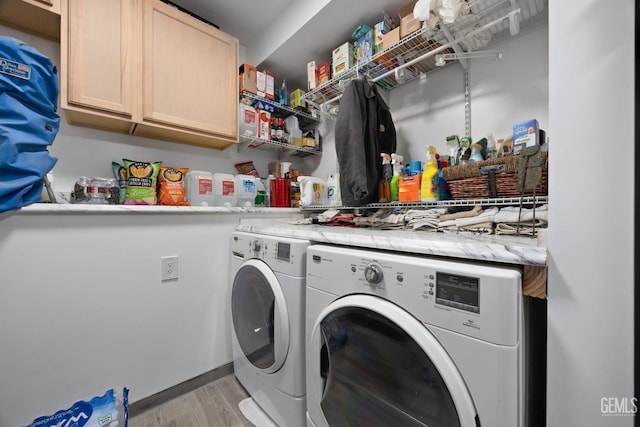 clothes washing area featuring cabinets, washer and clothes dryer, and light hardwood / wood-style floors