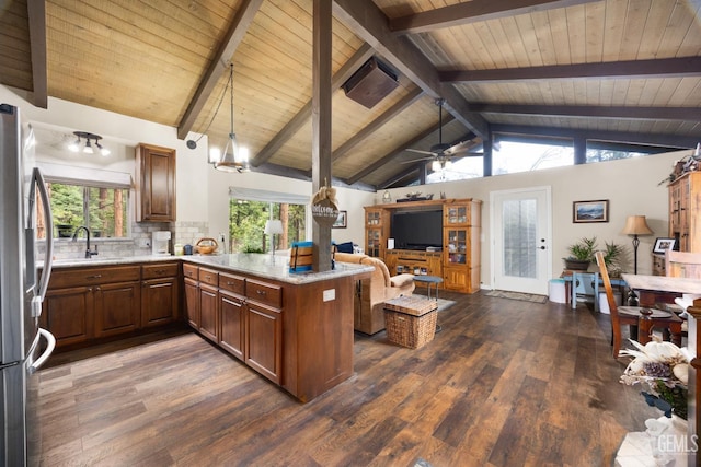 kitchen featuring stainless steel fridge, vaulted ceiling with beams, tasteful backsplash, decorative light fixtures, and kitchen peninsula