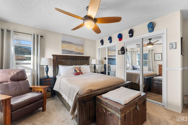 carpeted bedroom featuring a textured ceiling, two closets, and ceiling fan