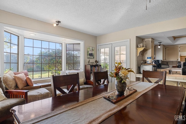 dining area with french doors, plenty of natural light, and a textured ceiling