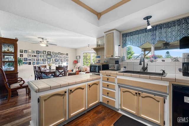 kitchen with kitchen peninsula, tile countertops, dark wood-type flooring, and sink