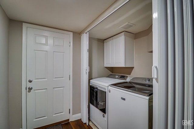 laundry area featuring washer and dryer, dark hardwood / wood-style flooring, and cabinets