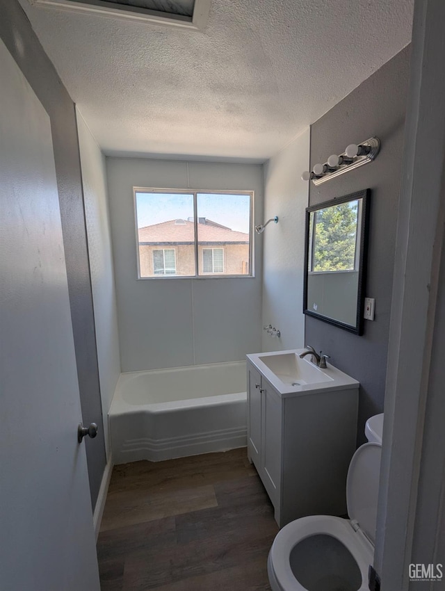 full bathroom with wood finished floors, toilet, healthy amount of natural light, a textured ceiling, and vanity
