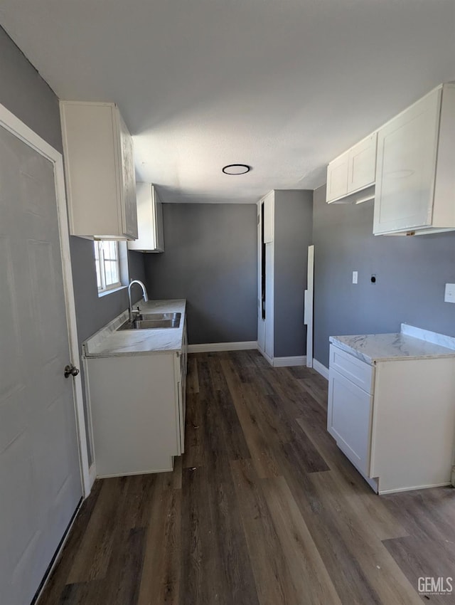 kitchen featuring a sink, dark wood-style floors, white cabinets, and baseboards
