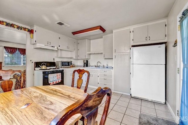 kitchen featuring black range with gas stovetop, white refrigerator, light tile patterned floors, and sink