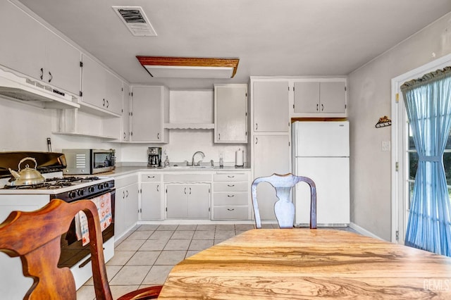 kitchen with plenty of natural light, white appliances, sink, and light tile patterned floors