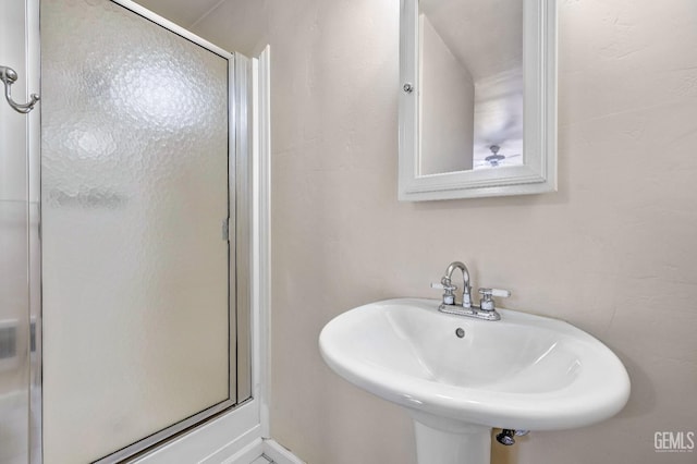 bathroom with sink and a shower with door