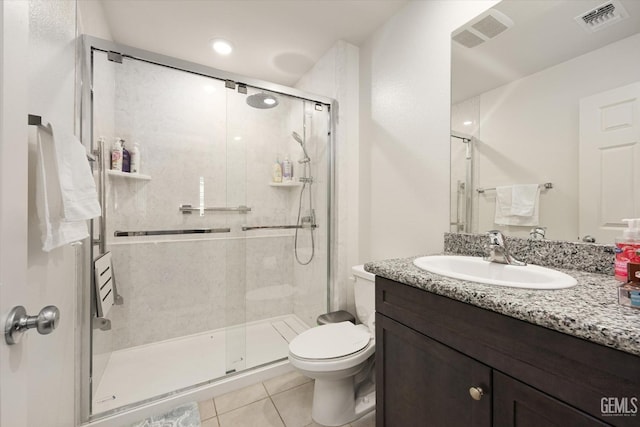 bathroom featuring toilet, vanity, tile patterned floors, and a shower with shower door