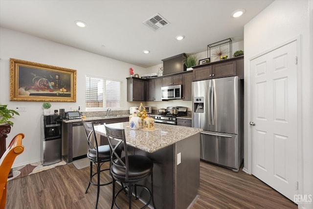 kitchen featuring a breakfast bar area, dark brown cabinetry, a kitchen island, and stainless steel appliances