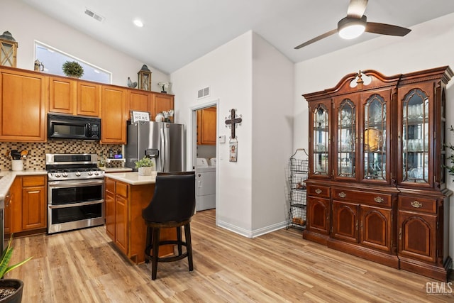 3010 Tea Rose St, Bakersfield, CA 93311 - kitchen featuring appliances with stainless steel finishes, washing machine and clothes dryer, light countertops, backsplash, and brown cabinets