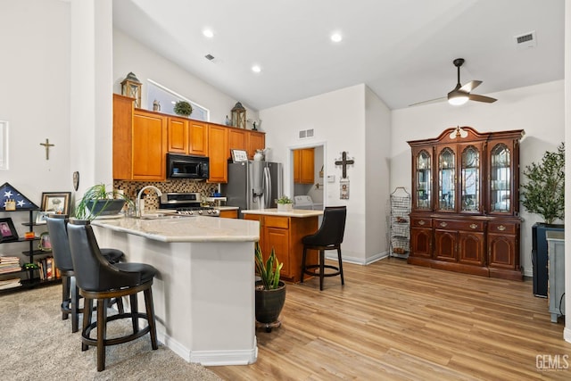 3010 Tea Rose St, Bakersfield, CA 93311 - kitchen with stainless steel appliances, a kitchen bar, brown cabinets, a peninsula, and a ceiling fan