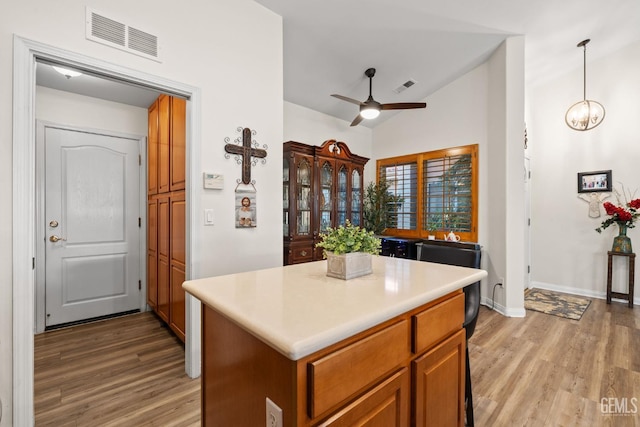 3010 Tea Rose St, Bakersfield, CA 93311 - kitchen featuring light wood finished floors, ceiling fan, a kitchen island, brown cabinets, and vaulted ceiling
