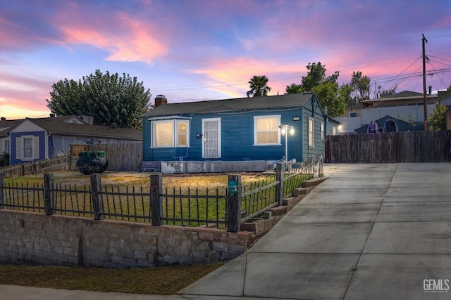 view of front of house with a fenced front yard, a front yard, concrete driveway, and a chimney