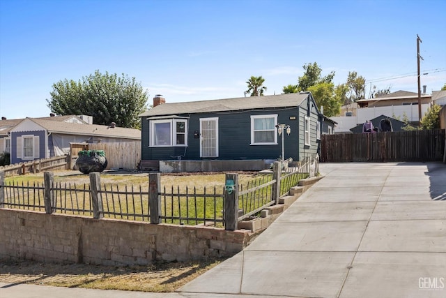 bungalow with a fenced front yard, a front yard, a chimney, and driveway