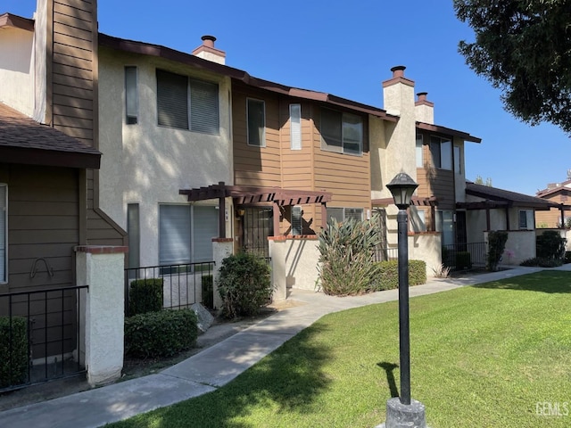 view of property featuring a pergola and a front yard