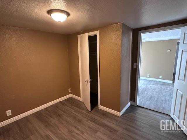 780 Mayer Ln, Bakersfield, CA 93263 - unfurnished bedroom with a textured ceiling, dark wood-style flooring, baseboards, a closet, and a textured wall
