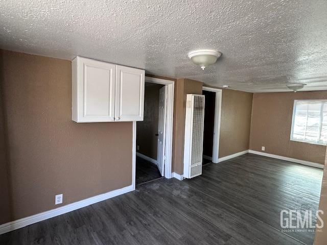 780 Mayer Ln, Bakersfield, CA 93263 - unfurnished room with a heating unit, dark wood-style floors, baseboards, and a textured ceiling