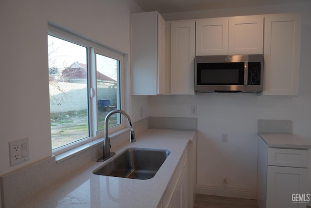 kitchen with sink, white cabinetry, and light stone countertops