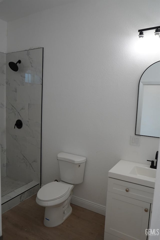 bathroom featuring vanity, toilet, tiled shower, and wood-type flooring