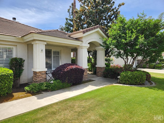 8707 Beau Maison Way, Bakersfield, CA 93311 - view of front of house featuring a tile roof, stucco siding, a front lawn, stone siding, and covered porch