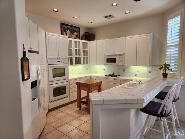 8707 Beau Maison Way, Bakersfield, CA 93311 - kitchen with a sink, white appliances, a peninsula, backsplash, and white cabinets
