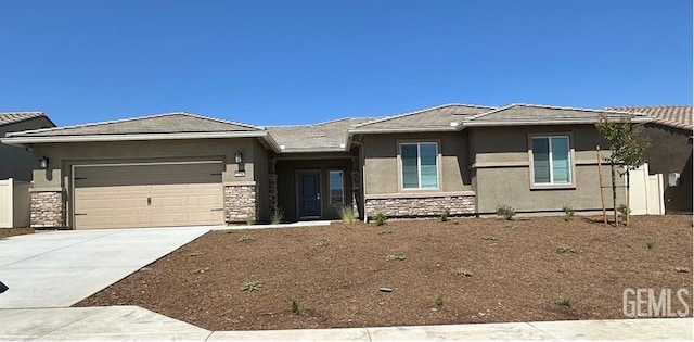 prairie-style house featuring a tile roof, stucco siding, concrete driveway, a garage, and stone siding