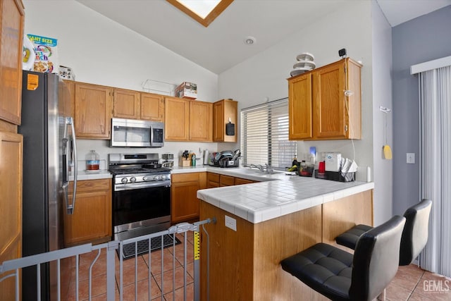 7507 Hidden Bridge Dr, Bakersfield, CA 93313 - kitchen featuring stainless steel appliances, light tile patterned floors, a peninsula, a breakfast bar area, and high vaulted ceiling