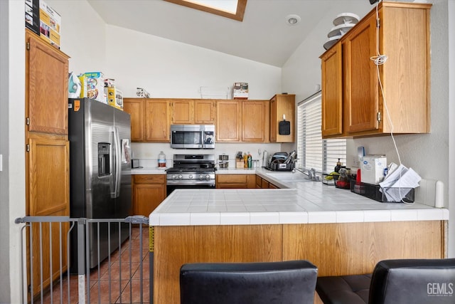 7507 Hidden Bridge Dr, Bakersfield, CA 93313 - kitchen featuring stainless steel appliances, a peninsula, dark tile patterned flooring, brown cabinets, and high vaulted ceiling