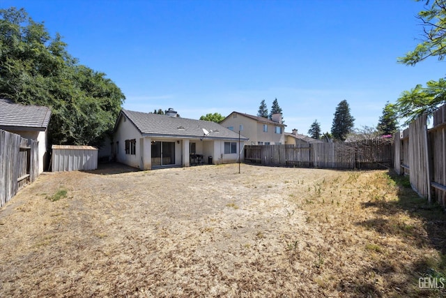 7507 Hidden Bridge Dr, Bakersfield, CA 93313 - rear view of house with a fenced backyard, a chimney, a shed, and stucco siding