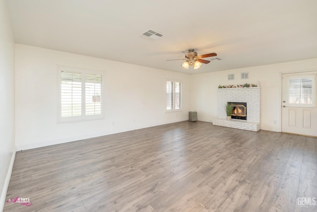 unfurnished living room with a wealth of natural light, visible vents, and wood finished floors