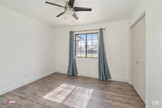 unfurnished bedroom featuring ceiling fan, a closet, wood finished floors, and baseboards