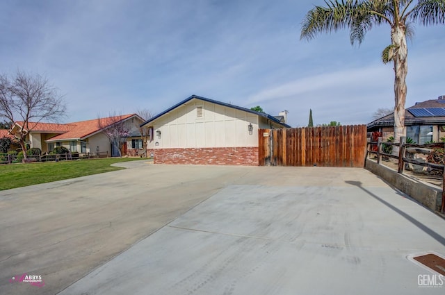 view of property exterior featuring fence, a lawn, and brick siding